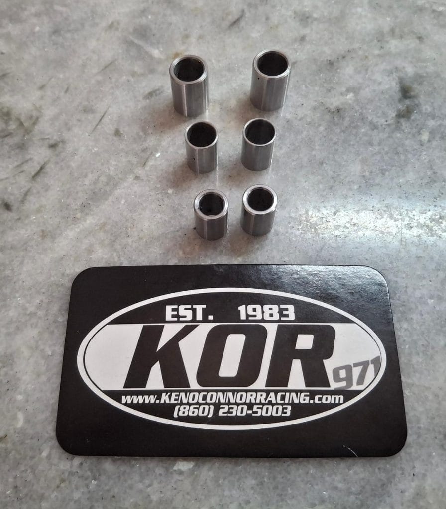 Six metal racing spacers on a concrete surface with Ken OConnor Racing logo mat.